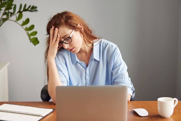 Retrato de hermosa empresaria aburrida, apoyándose en su codo en agotamiento