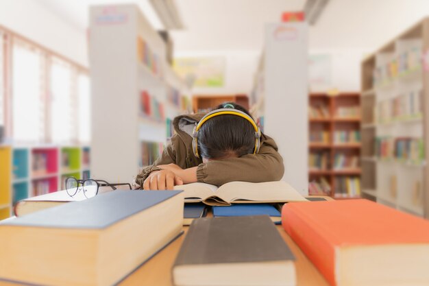 Retrato de una hermosa estudiante morena cansada sentada entre los libros