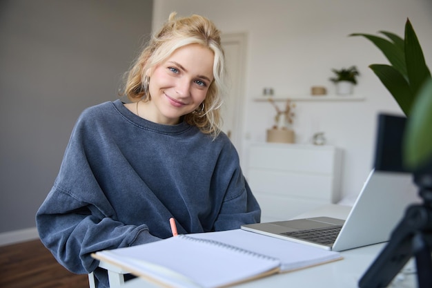 Foto gratuita retrato de una hermosa estudiante sonriente que estudia en casa concepto de educación a distancia se sienta en una habitación