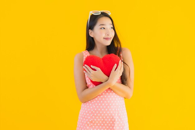 Retrato hermosa joven asiática con almohada de corazón