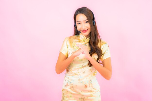 Retrato hermosa joven asiática atención del centro de llamadas del cliente en la pared de color rosa