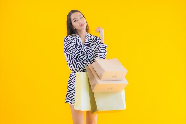 Retrato hermosa joven asiática con bolsa de compras de minoristas y grandes almacenes en amarillo