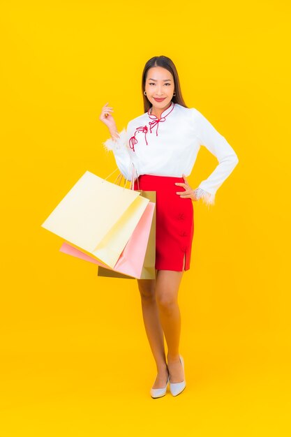 Retrato hermosa joven asiática con bolsa de compras y tarjeta de crédito en amarillo
