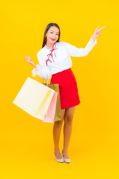 Retrato hermosa joven asiática con bolsa de compras y tarjeta de crédito en amarillo