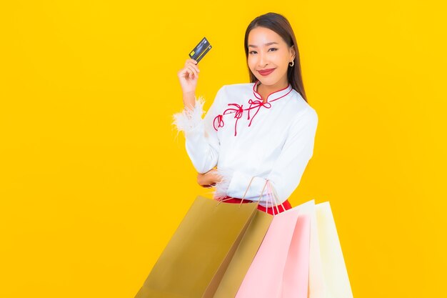 Retrato hermosa joven asiática con bolsa de compras y tarjeta de crédito en amarillo