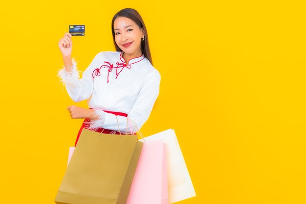 Retrato hermosa joven asiática con bolsa de compras y tarjeta de crédito en amarillo