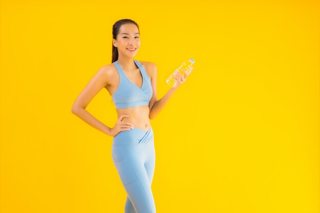 Retrato hermosa joven asiática con botella de agua en amarillo