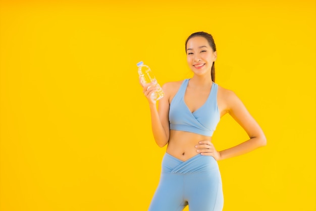 Retrato hermosa joven asiática con botella de agua en amarillo