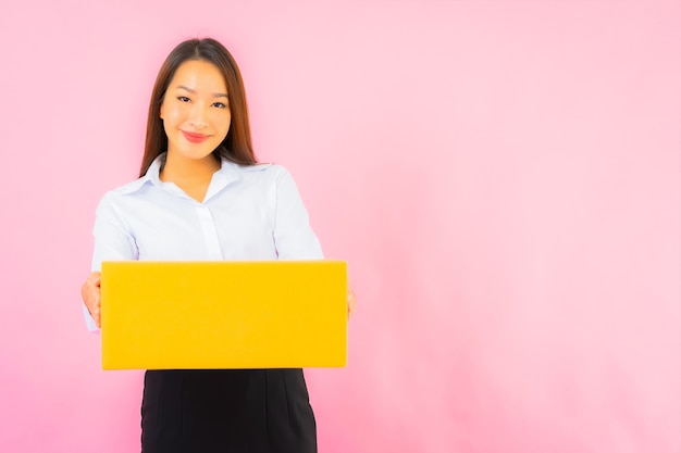 Retrato hermosa joven asiática con caja de embalaje lista para enviar en la pared de color rosa