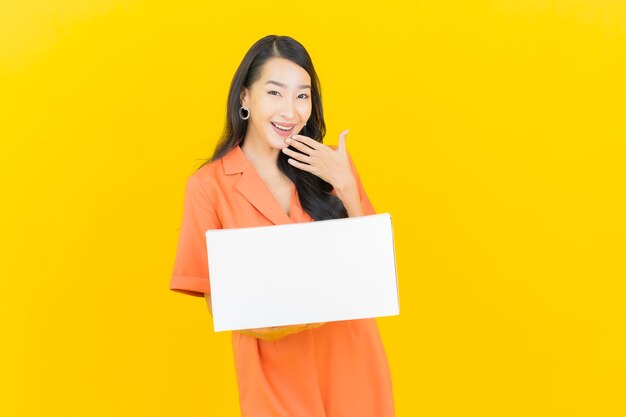 Retrato hermosa joven asiática con caja lista para enviar en amarillo