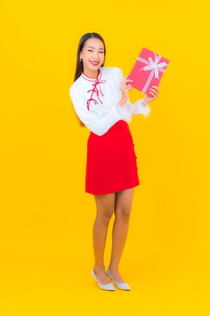 Retrato hermosa joven asiática con caja de regalo roja sobre amarillo