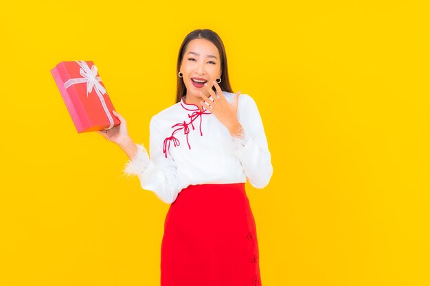 Retrato hermosa joven asiática con caja de regalo roja sobre amarillo