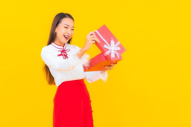 Retrato hermosa joven asiática con caja de regalo roja sobre amarillo