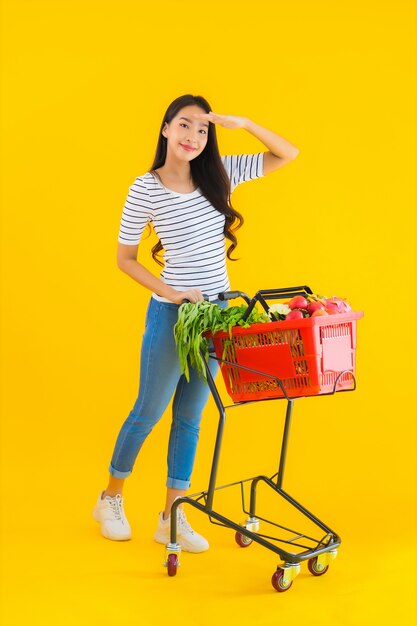 Retrato hermosa joven asiática con carrito de supermercado del supermercado en el centro comercial