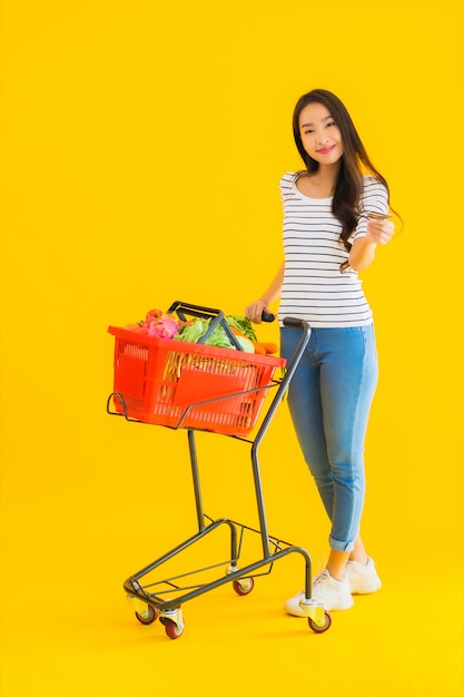Retrato hermosa joven asiática con carrito de supermercado del supermercado en el centro comercial