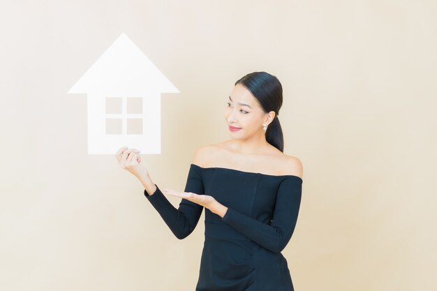 Retrato hermosa joven asiática con casa o cartel de papel casero en amarillo