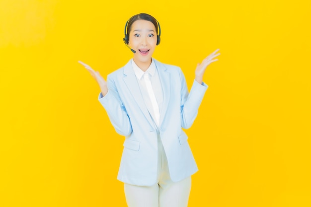 Foto gratuita retrato hermosa joven asiática con centro de servicio de atención al cliente de call center en amarillo