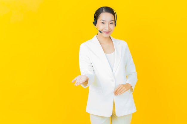 Retrato hermosa joven asiática con centro de servicio de atención al cliente de call center en la pared de color amarillo