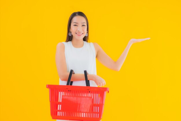 Retrato hermosa joven asiática con cesta de la compra para ir de compras en el supermercado