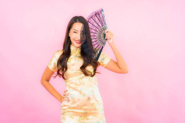 Retrato hermosa joven asiática con concepto de año nuevo chino y ventilador en la pared de color