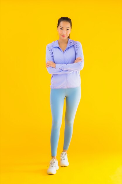 Retrato hermosa joven asiática deporte mujer lista para hacer ejercicio en amarillo