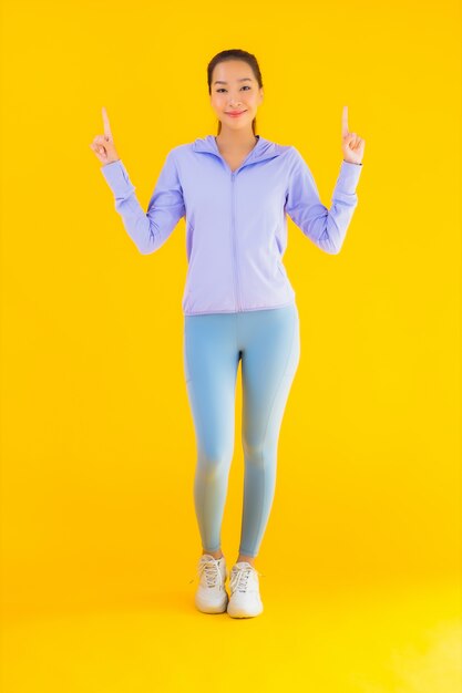 Retrato hermosa joven asiática deporte mujer lista para hacer ejercicio en amarillo