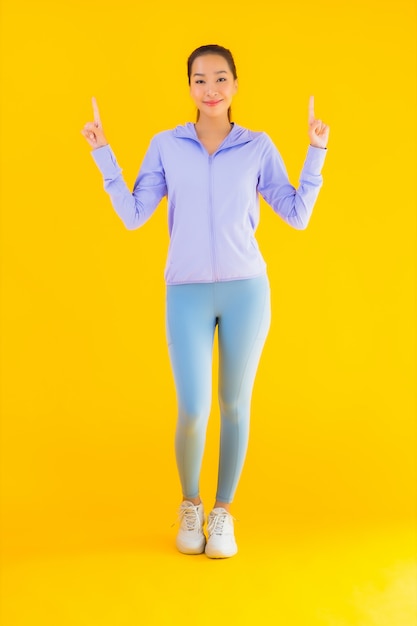 Retrato hermosa joven asiática deporte mujer lista para hacer ejercicio en amarillo