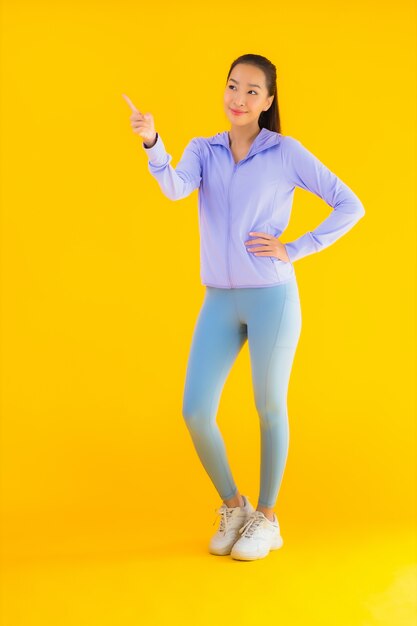 Retrato hermosa joven asiática deporte mujer lista para hacer ejercicio en amarillo