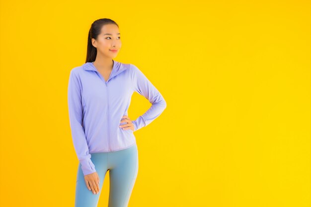 Retrato hermosa joven asiática deporte mujer lista para hacer ejercicio en amarillo