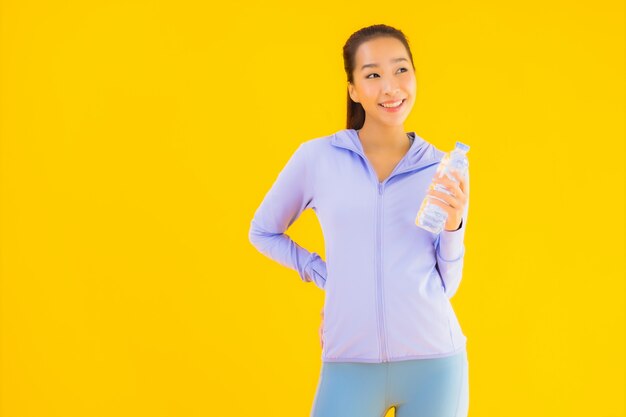 Retrato hermosa joven asiática deporte mujer lista para hacer ejercicio en amarillo