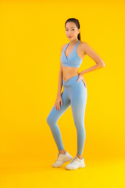 Retrato hermosa joven asiática deporte mujer lista para hacer ejercicio en amarillo