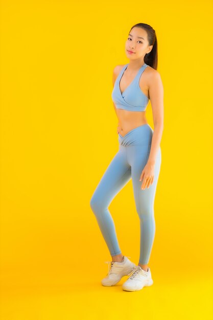 Retrato hermosa joven asiática deporte mujer lista para hacer ejercicio en amarillo