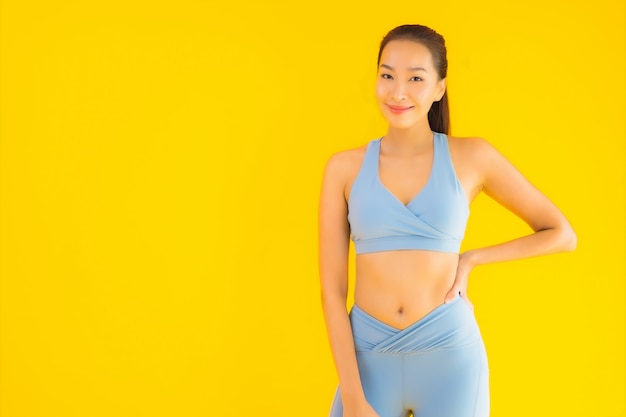 Retrato hermosa joven asiática deporte mujer lista para hacer ejercicio en amarillo