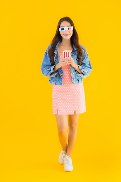 Retrato hermosa joven asiática disfruta feliz con palomitas de maíz y mira la película