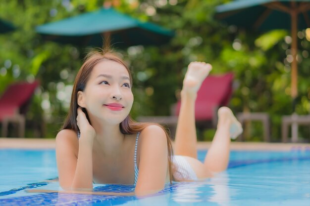 Retrato hermosa joven asiática disfruta relajarse sonrisa ocio alrededor de la piscina al aire libre en el hotel