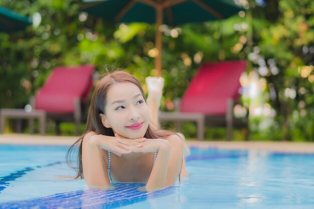 Retrato hermosa joven asiática disfruta relajarse sonrisa ocio alrededor de la piscina al aire libre en el hotel