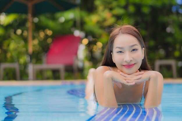 Retrato hermosa joven asiática disfruta relajarse sonrisa ocio alrededor de la piscina al aire libre en el hotel