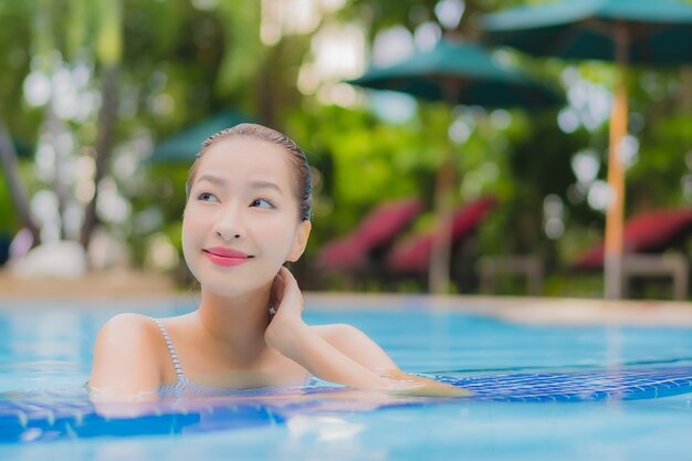 Retrato hermosa joven asiática disfruta relajarse sonrisa ocio alrededor de la piscina al aire libre en el hotel