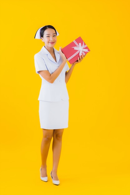 Retrato hermosa joven asiática enfermera tailandesa con caja de regalo roja