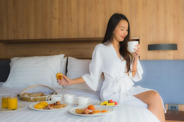 Retrato hermosa joven asiática feliz disfrutar con desayuno en la cama en el dormitorio