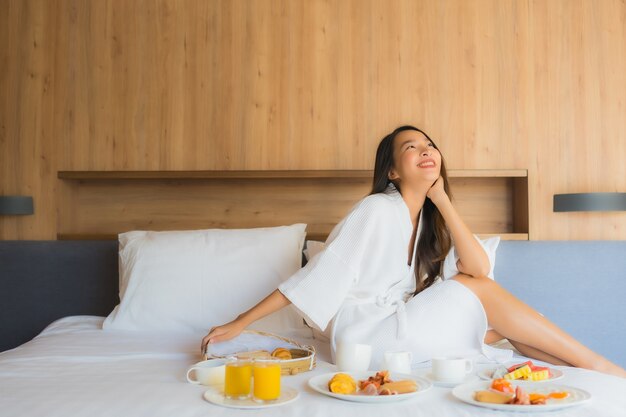 Retrato hermosa joven asiática feliz disfrutar con desayuno en la cama en el dormitorio