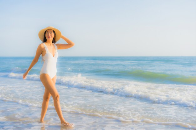 Retrato hermosa joven asiática feliz sonrisa alrededor del mar océano playa