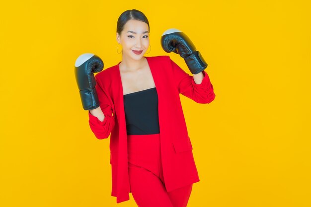 Retrato hermosa joven asiática con guante de boxeo en amarillo