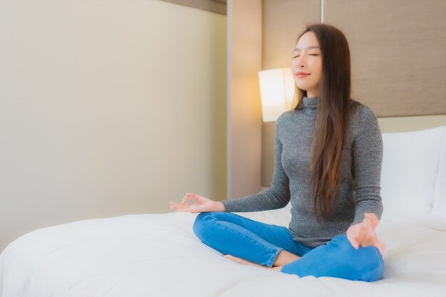 Retrato de hermosa joven asiática haciendo meditación en la cama