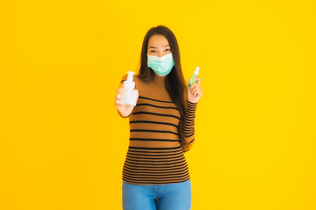 Retrato hermosa joven asiática con máscara de aerosol de alcohol y botella de gel en la mano para proteger de coronavirus o covid19