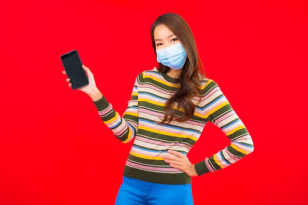Retrato hermosa joven asiática con máscara de desgaste de teléfono para proteger covid19
