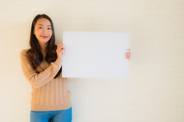 Retrato hermosa joven asiática mostrar pizarra en blanco de papel blanco