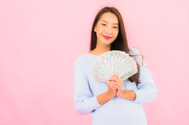 Retrato hermosa joven asiática con mucho dinero en efectivo y dinero en la pared de color rosa