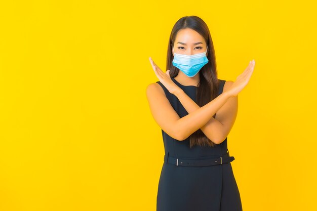 Retrato hermosa joven asiática mujer de negocios usar máscara para proteger covid19 sobre fondo amarillo