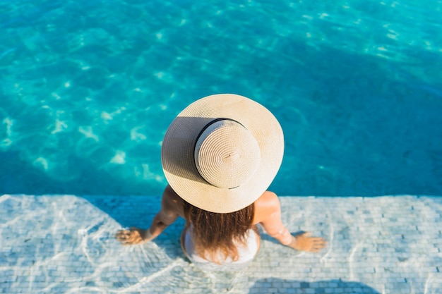 Retrato hermosa joven asiática relajante alrededor de la piscina al aire libre con vistas a la ciudad